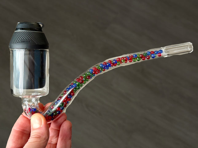 Hand holding the Puffco Proxy J-Hook with the Proxy installed, showing size and bead-filled cooling.